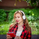 Femeie ascultând muzică la căști, exemplificând beneficiile aduse de terapia prin muzică pentru relaxare și sănătate mintală.